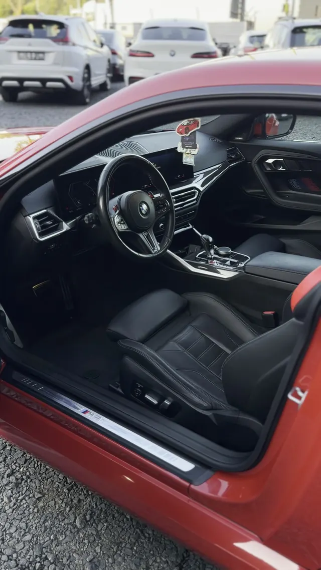 Otwarte drzwi BMW M2, widoczny czysty próg i czarna skórzana tapicerka