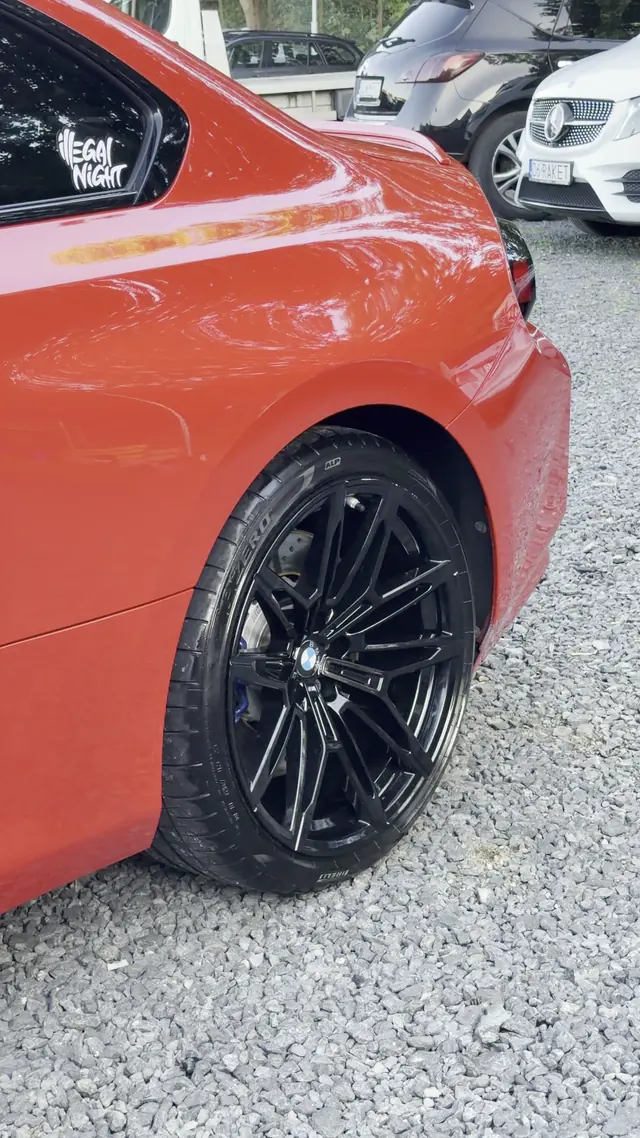 Tylne koło BMW M2 z czarną felgą i opona po czyszczeniu, bok auta w czerwonym lakierze