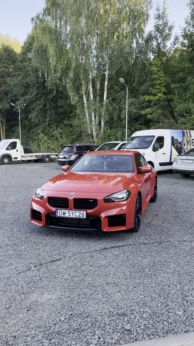Czerwone BMW M2 zaparkowane przed studio po skończonej pracy